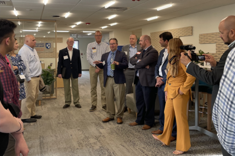 A UNH and business partnership meet and greet, people in suits with name tags in a campus room.